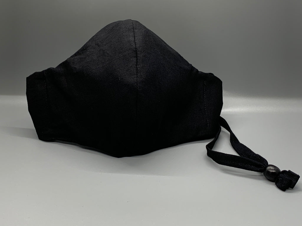 Handmade Triple Layer Cotton Facemask. Solid black cotton. Black filter pocket. Overhead/Back of Head cotton loop from same fabric. Adjustable Wood Bead for perfect fit. This mask has no nose wire-the adjustable overhead loop gives you a snug fit.  Cut from one cloth-meaning fabric is same and where your pattern lies may vary. non-returnable/non-refundable. non medical grade. not a replacement for medical grade personal protective equipment (PPE), surgical masks, N95s, or social distancing. Follow all recom