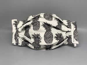 Handmade Triple Layer Cotton Facemask. Pineapples drawn in black on white cotton, accordion style mask. Fabric enclosed nose wire. Comfy adjustable white elastic earloops. This mask has no filter pocket. Cut from one cloth-meaning fabric is same and where your pattern lies may vary. non-returnable/non-refundable. non medical grade. not a replacement for medical grade personal protective equipment (PPE), surgical masks, N95s, or social distancing. Follow all recommended CDC guidelines.