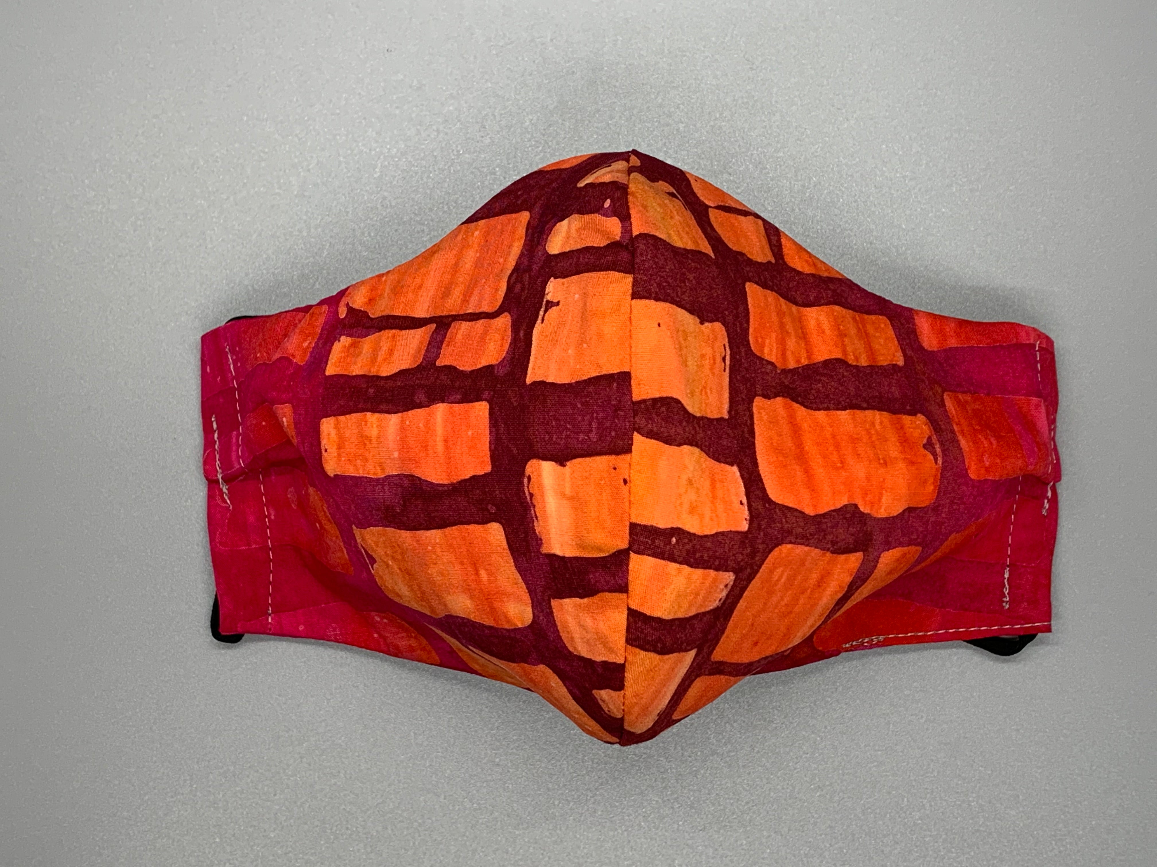 Takes me back to Hawaii's fiery sunsets. Hues of purple and orange with rectangle shapes throughout. Gray filter pocket. Fabric enclosed nose wire. Comfy adjustable black earloops.  Cut from one cloth-meaning fabric is same and where your pattern lies may vary. non-returnable/non-refundable. non medical grade. not a replacement for medical grade personal protective equipment (PPE), surgical masks, N95s, or social distancing. follow all recommended CDC guidelines.