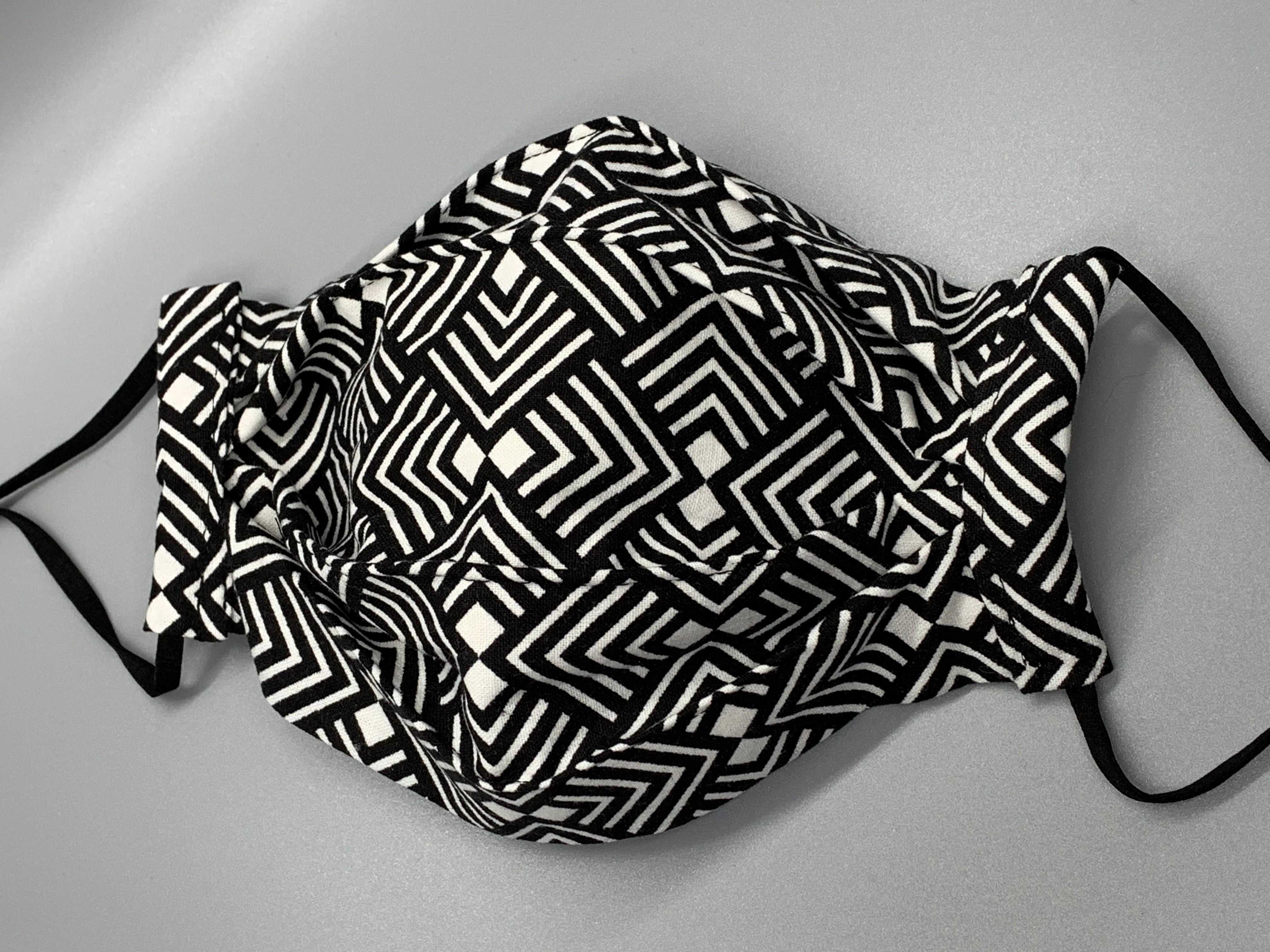 Black and white lined pattern repeats on this bold fabric. Fabric enclosed nose wire. Comfy adjustable black elastic earloops. This mask has no filter pocket. It still has 3 layers of cotton plus one layer non woven interfacing. 