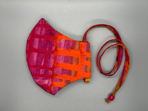 Takes me back to Hawaii's fiery sunsets.  Hues of purple and orange with rectangle shapes throughout. Gray filter pocket. Overhead/Back of Head cotton loop from same fabric. Adjustable Wood Bead for perfect fit. This mask has no nose wire-the adjustable overhead loop gives you a snug fit.