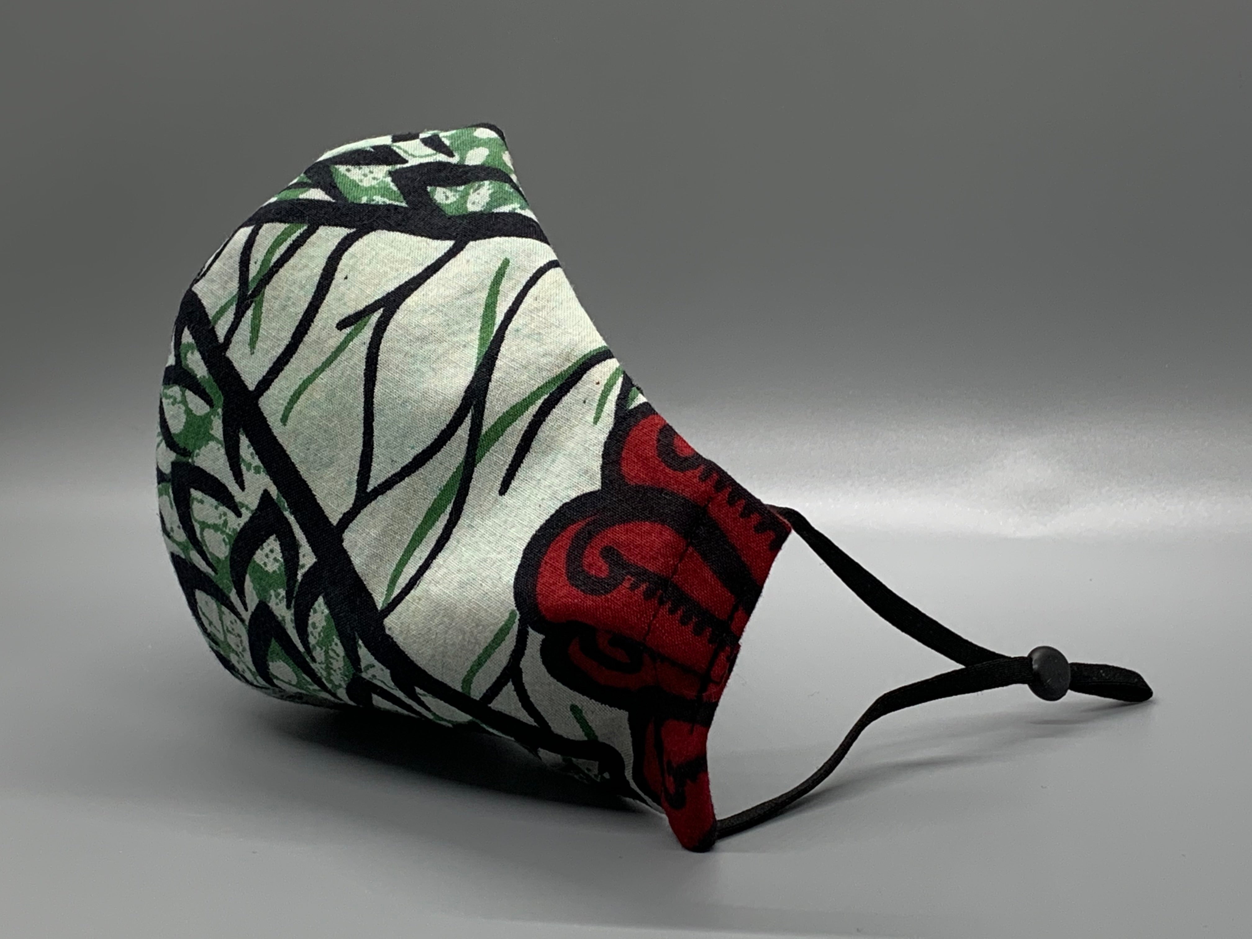 Cool green and black vine with orange, foam, green, and red pattern. Gray filter pocket. Fabric enclosed nose wire. Comfy adjustable black elastic earloops.   Cut from one cloth-meaning fabric is same and where your pattern lies may vary. non-returnable/non-refundable. non medical grade. not a replacement for medical grade personal protective equipment (PPE), surgical masks, N95s, or social distancing. Follow all recommended CDC guidelines.