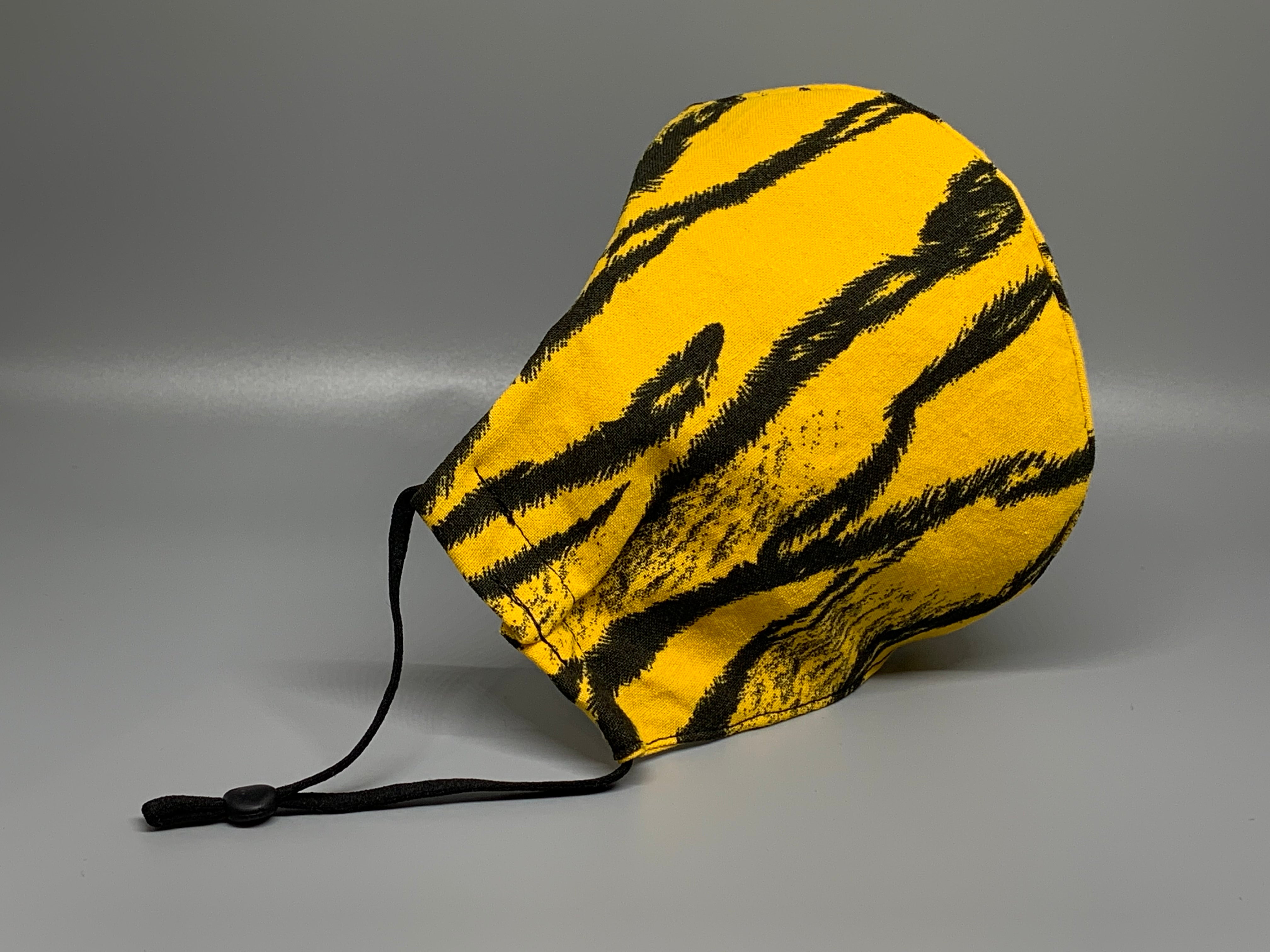 Black Tiger stripes on a deeper yellow cotton. Gray filter pocket. Fabric enclosed nose wire. Comfy adjustable black elastic earloops. 