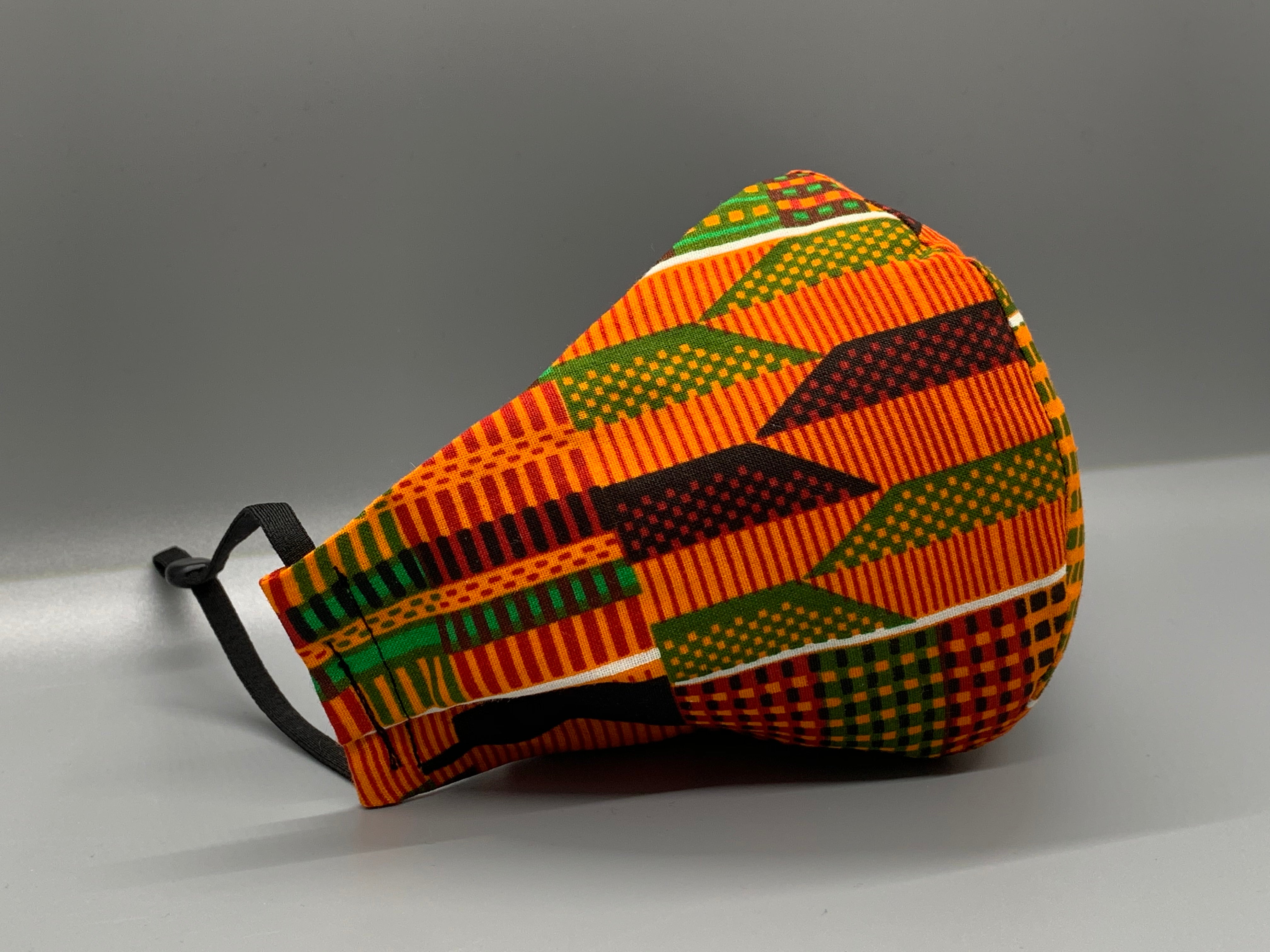 Handmade triple layer cotton facemask. Kente Inspired cotton. Vibrant patterns on orange background. Fabric enclosed nose wire. Grey filter pocket. Comfy adjustable black elastic ear loops.