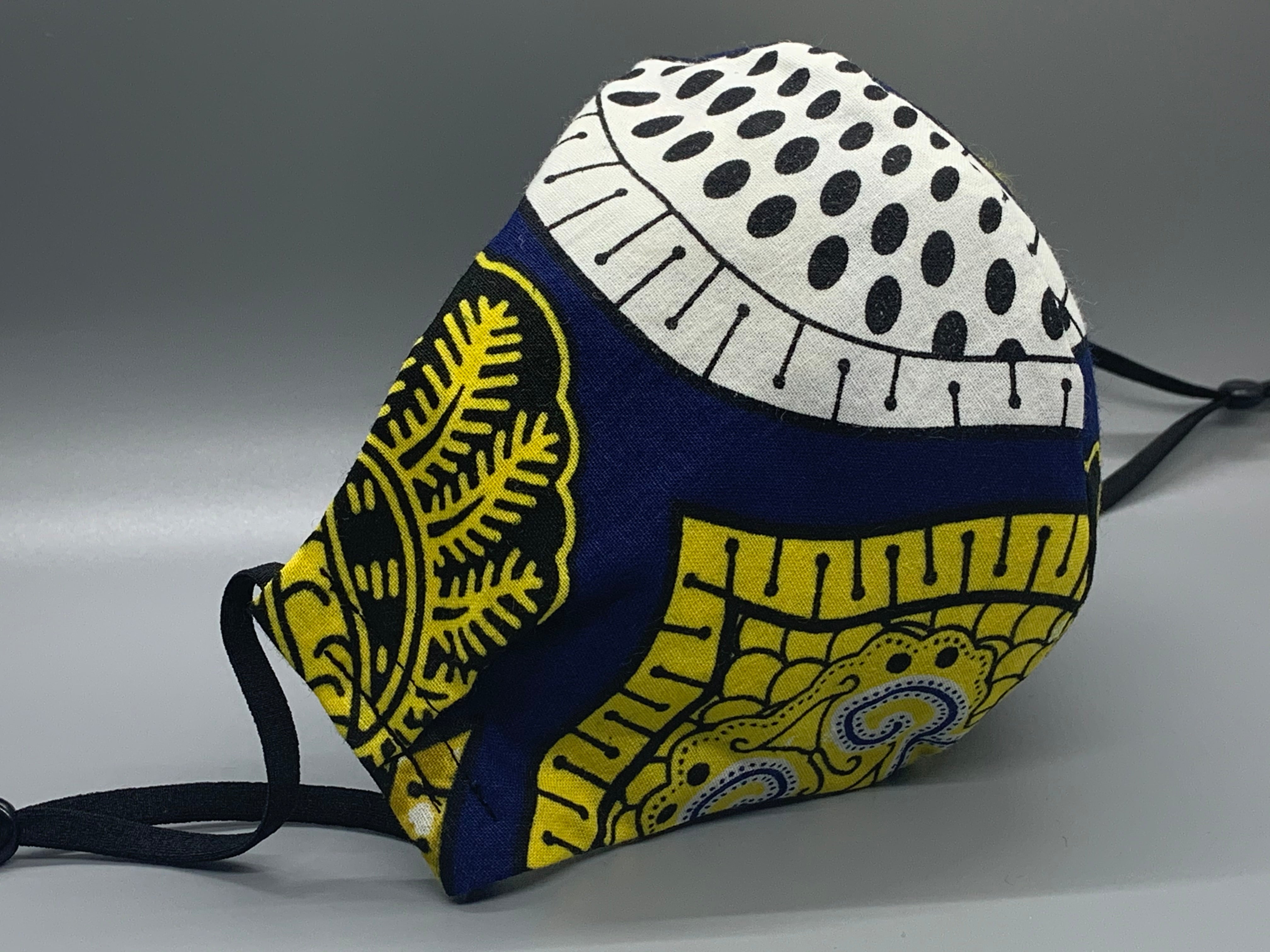 Handmade triple layer cotton facemask. Gorgeous blue, fabric with symbols/pattern in yellow white and black. The ream stated this fabric is from Ghana (or inspired by their amazing prints). Fabric enclosed nose wire. Grey filter pocket. Comfy adjustable black elastic ear loops.  Edit alt text