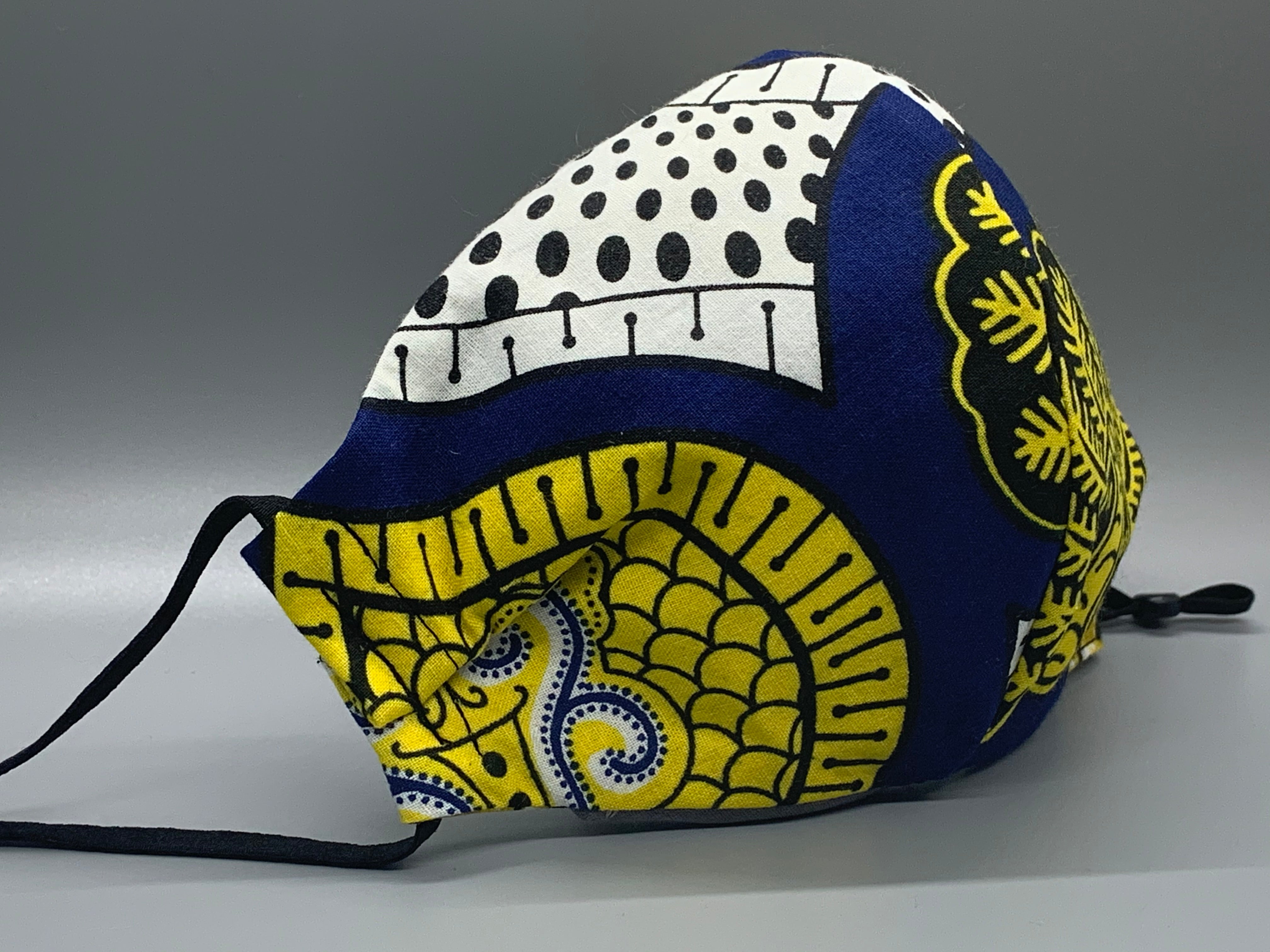 Handmade triple layer cotton facemask. Gorgeous blue, fabric with symbols/pattern in yellow white and black. The ream stated this fabric is from Ghana (or inspired by their amazing prints). Fabric enclosed nose wire. Grey filter pocket. Comfy adjustable black elastic ear loops.