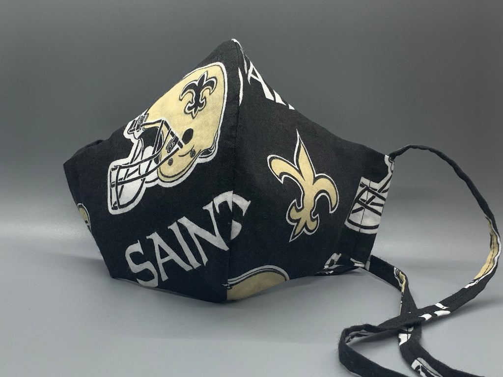 Handmade triple layer cotton facemask. Saints Fans, get your gear! Black filter pocket. Overhead/Back of Head cotton loop from same fabric. Adjustable Wood Bead for perfect fit. This mask has no nose wire-the adjustable overhead loop gives you a snug fit.